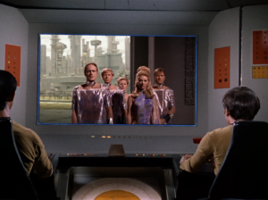 The bridge crew views the distress call from Scalos.