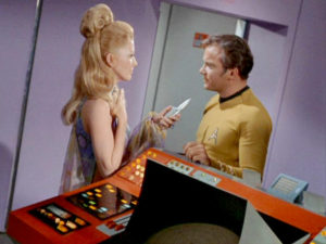 Deelah threatens Kirk with her phaser weapon.