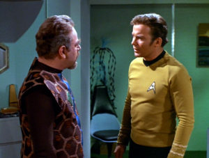 Kirk makes an agonized face at the Gideon council head