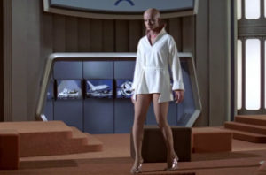 Probe Ilia, wearing, for some reason, a short-short bathrobe and lucite heels??